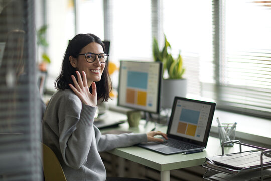 Portrait of Young Adult Caucasian Woman Smiling and Waving While Working - Powered by Adobe