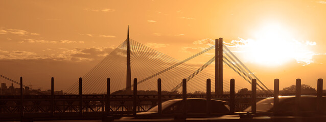 sunset evening red blue orange sky, and blur blurred cars came and went on Ada bridge View from Gazela bridge New Old railway bridge