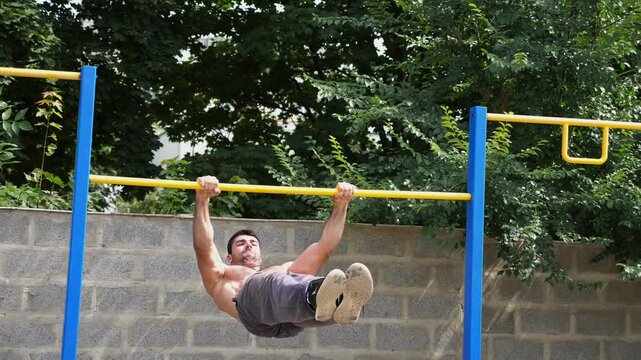 Athletic man performing dynamic workout routine on parallel bars, showcasing strength and control through progressive movements in a vibrant outdoor training environment