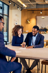 African-American Man and Caucasian Woman Sign Documents During a Business Meeting in a Bright Modern Office
