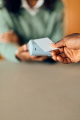 African-American Woman Handles Card Payment With Card Reader During Transaction at Desk