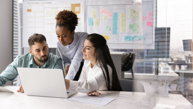 International business team developing project on notebook in Agile office - Powered by Adobe