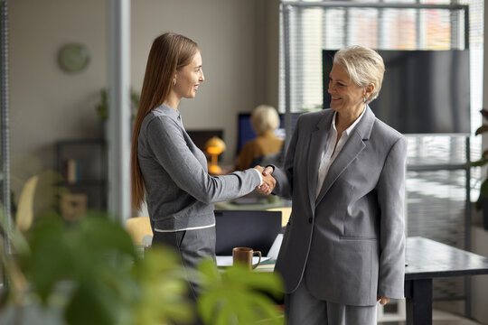 Middle Aged Caucasian Woman Shaking Hands with Young Adult Caucasian Woman