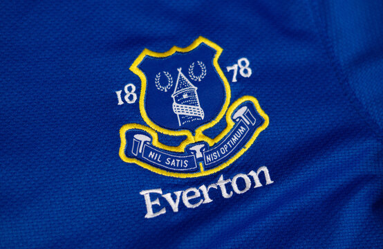 Embroidered Everton FC crest and logotype on close-up blue football jersey fabric textured.