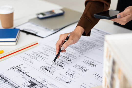 Close up hand of Architect or engineer professional holding pen working on blueprint , structural floor plans, triangular scale , Shop drawing , calculator, laptop and engineering tools.