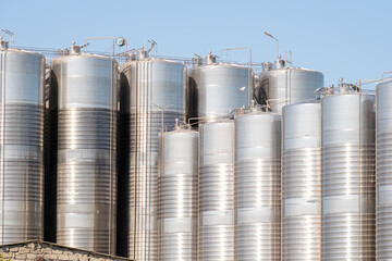 Large shiny stainless steel tanks stand outside a Winery on a sunny day