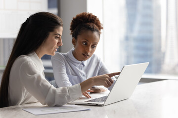 Young women office workers doing digital paperwork together using notebook