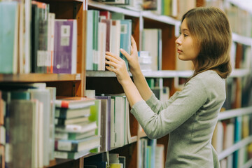 Student browsing academic literature in quiet university library, representing research, writing inspiration, and intellectual exploration.