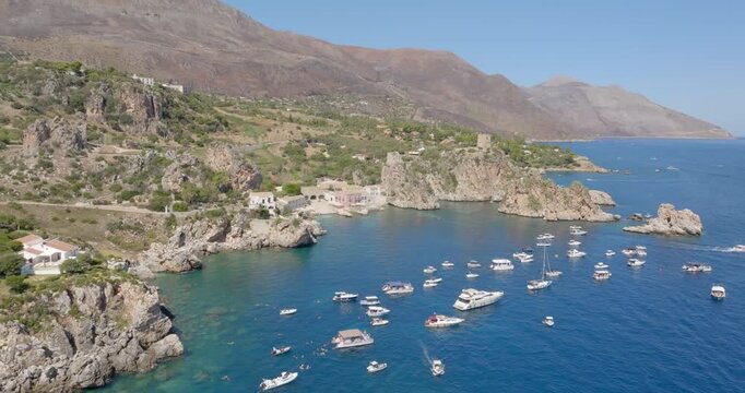 Aerial view of the Bay of Scopello, in the province of Trapani, Sicily, Italy. Boats are on vacation around the rocks in the Zingaro Nature Reserve.