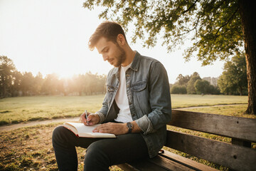 Hombre escribiendo en un parque al atardecer