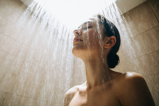 Mujer disfrutando de una ducha relajante bajo luz natural