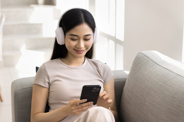 Woman in headphones enjoying digital content on smartphone