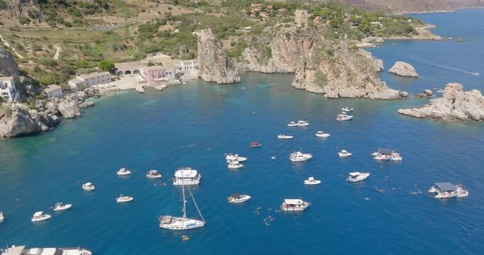 Aerial view of the Bay of Scopello, in the province of Trapani, Sicily, Italy. Boats are on vacation around the rocks in the Zingaro Nature Reserve.