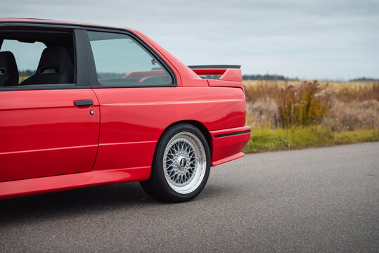 Rear of red BMW M3 E30 parked on a side of a rural road. Rear wheel, quarter panel, window of 1980s german coupe. Ukraine - October 19 2024