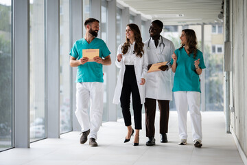 Diverse medical team walking and smiling in hospital corridor