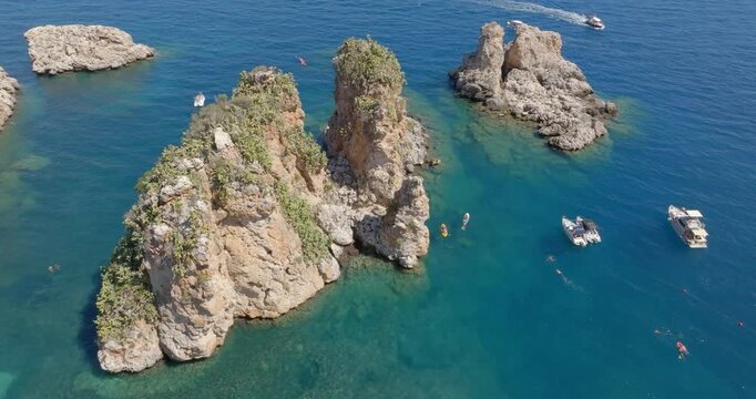 Aerial view of the Faraglioni rocks located in the Bay of Scopello, in the province of Trapani, Sicily, Italy. There are boats on holiday among the cliffs.
