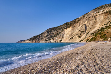 White pebbles on the beach at the foot of a rocky cliff on the island of Kefalonia