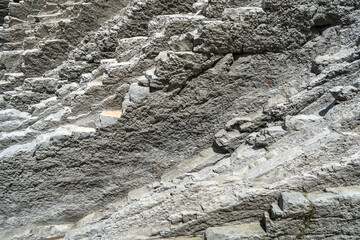 Layered rocks, flysch texture background. Sedimentary rock, striations stone pattern