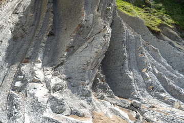 Layered rocks, flysch texture background. Sedimentary rock, striations stone pattern