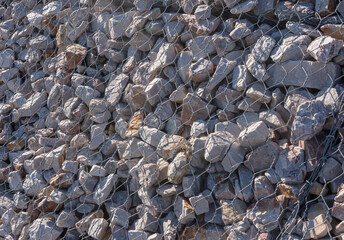 Gabion stone wall construction close up. New stone fence in wire grid, iron cage with rocks