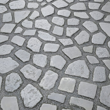 A close-up, angled view of an irregular gray flagstone pavement with dark gravel grout.
