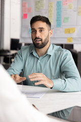 Naklejka premium Portrait focused young male business professional speak sitting at desk