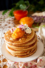 Rustic table setting with pancakes, caviar, sour cream, and onion - cozy homemade winter meal inspired by Nordic tradition.