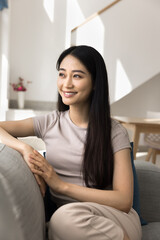 Obraz premium Chinese woman in casual clothes sits comfortable on cozy couch