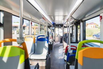 Fototapeta premium Bus interior with rows of empty seats and grab handles, showcasing modern public transportation and urban commuting space