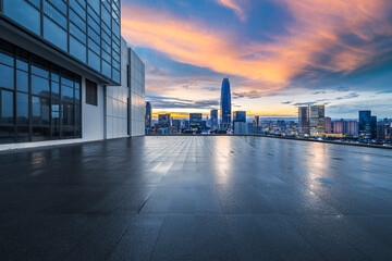Empty rooftop floor overlooking the modern city skyline with commercial buildings at sunset.