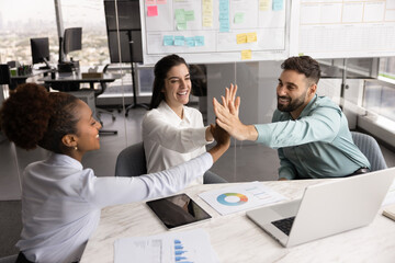 Enthusiastic diverse multiethnic business team celebrate achievement with high five
