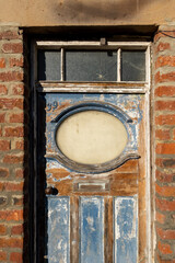 Old weathered doorway surrounded by warm brick wall. Arthitectural detail - vintage door in brick wall. Past meets present 