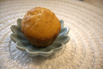 One single muffin on a small white plate, isolated on white background, close-up shot with Copy Space. Homemade dessert concept.