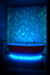 dramatic and immersive bathroom design, focused on ultraviolet and neon lighting. The central element is a sleek, free-standing bathtub with a dark, possibly reddish or plum-toned exterior.