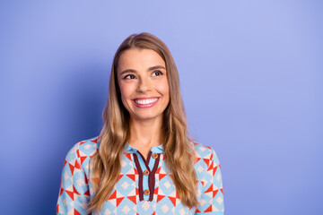 Young woman with long blonde hair wearing a colorful geometric sweater against a blue backdrop smiling warmly and confidently in a casual lifestyle portrait