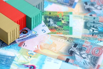 Kuwaiti dinar currency money bills and toy cargo containers close up. The concept of shipping and logistics