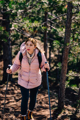 Woman hiking through forest with trekking poles