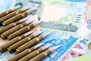 Bahraini dinar currency money bills and rifle bullets close up. The concept of warfare and gun selling