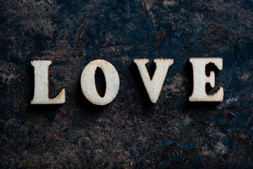 Wooden letters with the word love on an old rusty surface, closeup, top view. The concept of happiness, peace, brotherhood, beautiful world