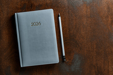 2026 gray notebook and pencil on wooden texture background, closeup, top view, copy space. Calendar planner, organizer, business event schedule concept
