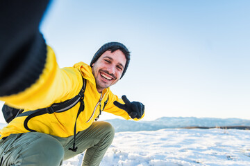 Young man wearing winter clothes taking selfie picture in winter snow mountain - Happy guy with...