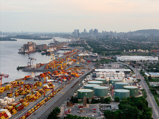 Fototapeta premium Aerial view of Montreal port with cargo containers, cranes and city skyline at sunset. g.