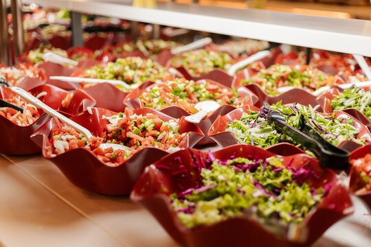 A vibrant salad bar is filled with an array of fresh vegetables and garnishes. The bowls showcase colorful ingredients, inviting guests to create their own healthy salads - Powered by Adobe