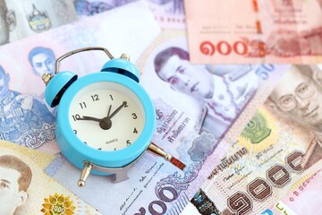 Thai baht currency money bills and alarm clock close up. The concept of time management and income
