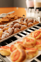 Various delicious pastries are arranged on trays, showcasing croissants, danishes, and sweet rolls. The warm morning light enhances their golden colors, inviting customers