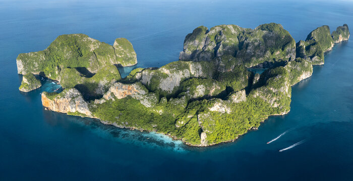 Aerial view of the majestic, verdant Phi Phi Islands rise sharply from the turquoise waters, boats leaving white wakes in their path, phi phi, krabi, Thailand.