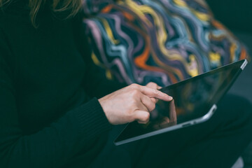 Woman scrolls through tablet. Closeup finger on black display Girl relaxing on sofa using tech.