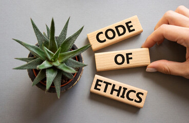Code of ethics symbol. Concept words Code of ethics on wooden blocks. Businessman hand. Beautiful...