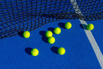 Scattered yellow tennis balls on a blue padel court The Aftermath of a Game