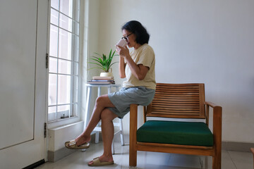 woman sitting over a window, enjoying her cup of hot coffee